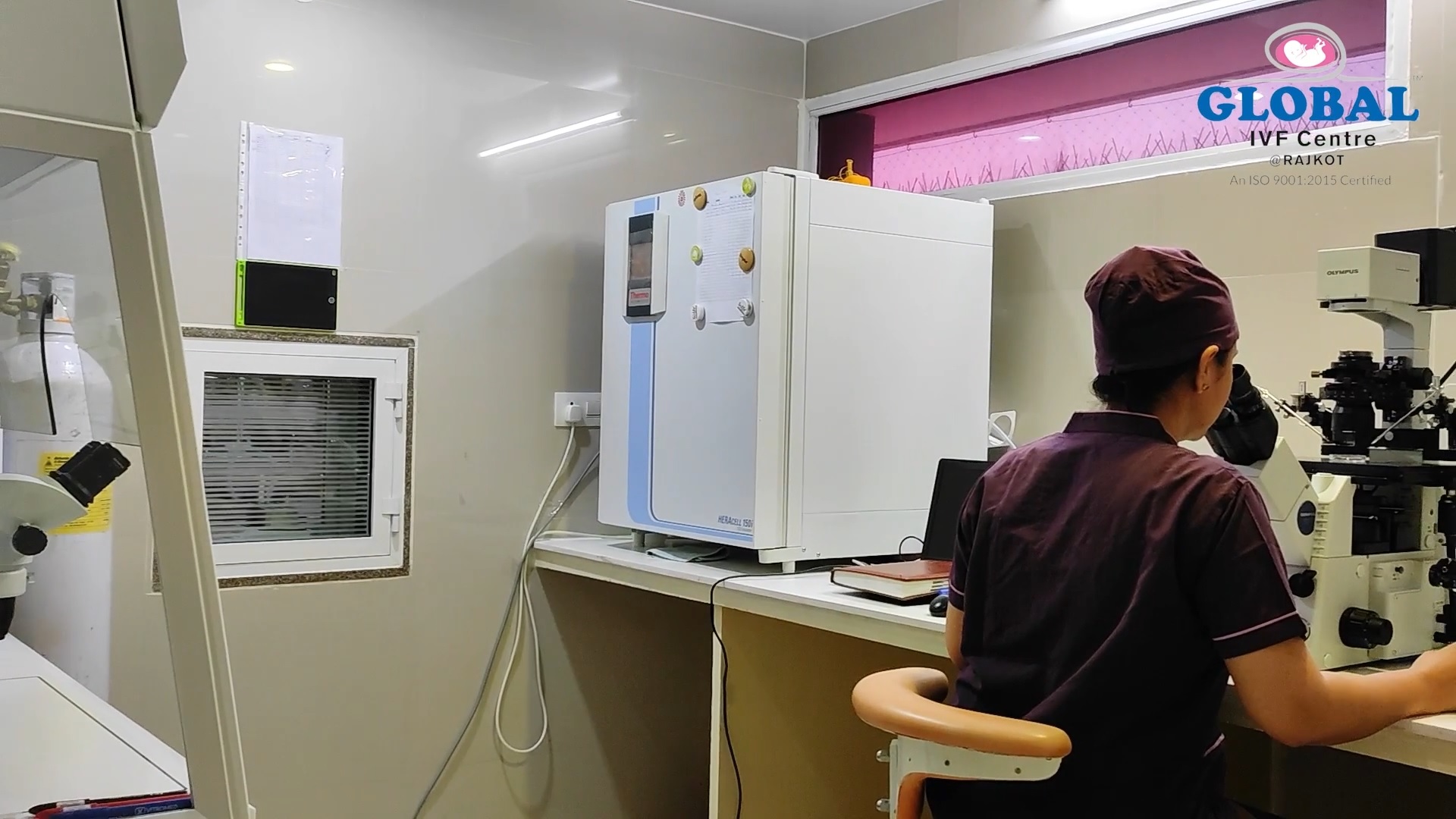 Embryologist at work inside the IVF laboratory with Thermo Heracell incubator and Olympus microscope